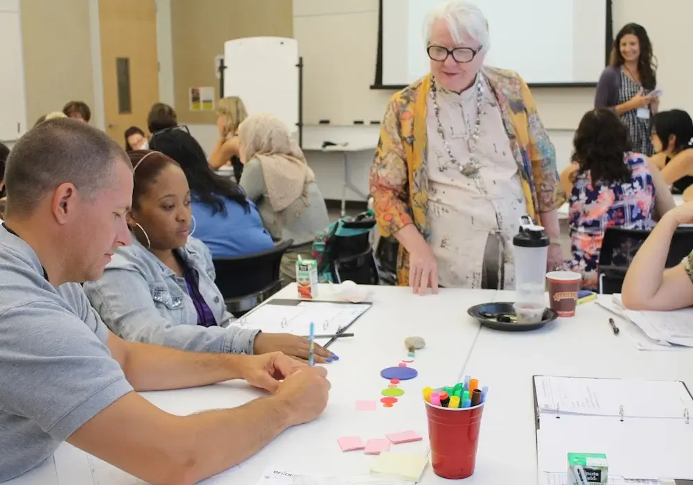 An instructor is surveying her class of adult students working on a project together.