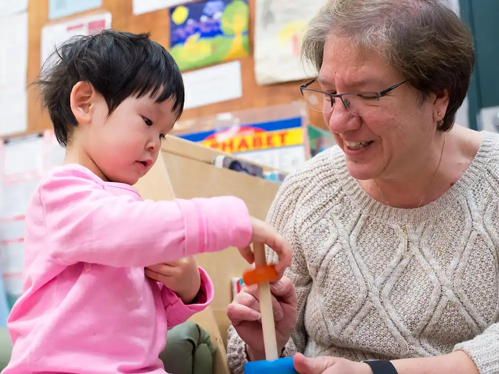 An educator and a child playing with blocks