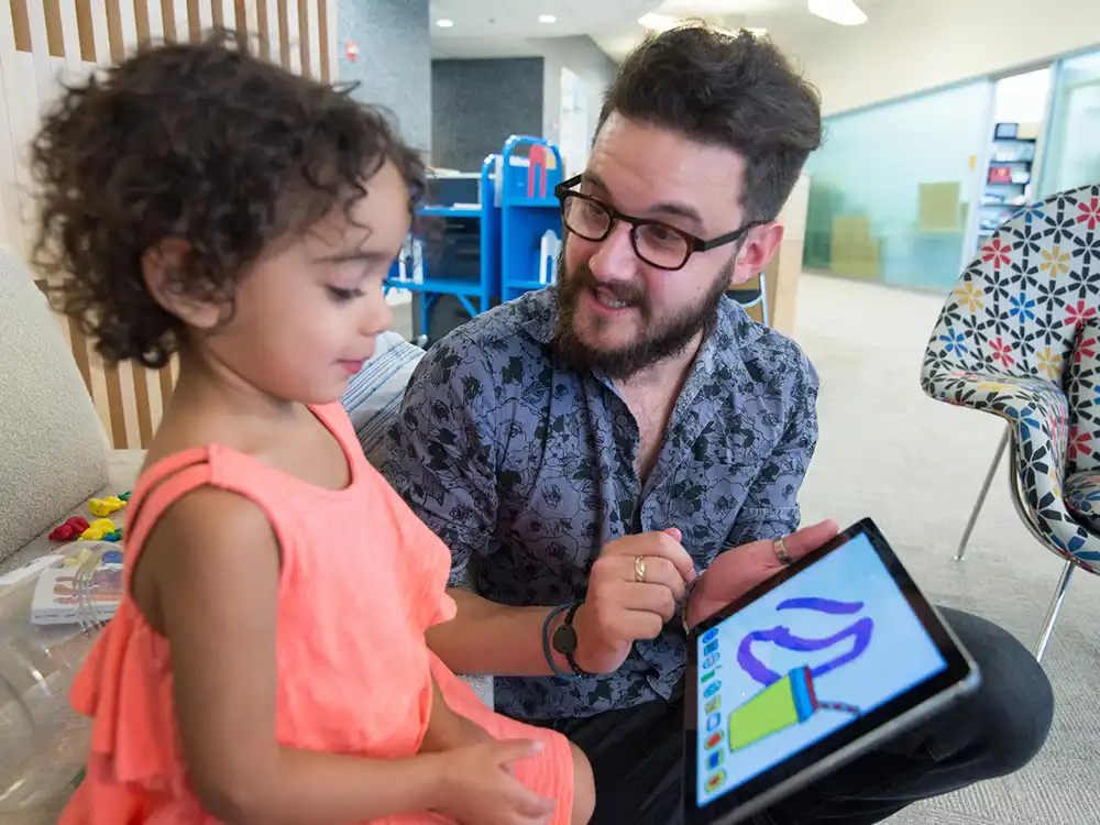 An educator and a child playing with a tablet